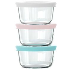 three glass containers stacked on top of each other, one with a pink lid and the other blue