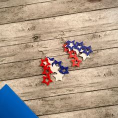 red, white and blue stars dangle earrings on wooden planked floor next to notebook