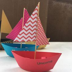 three paper boats sitting on top of a table next to each other, with the word unicorns written on them