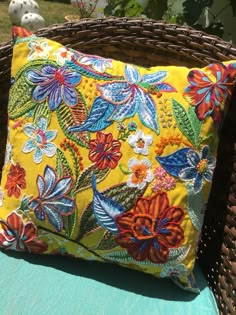 a yellow floral pillow sitting on top of a blue chair