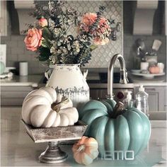 a kitchen counter with flowers and pumpkins on it