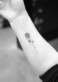 a woman's arm with a single rose tattoo on the left side of her wrist