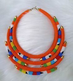 Do you intend to be creative in your dressing code and tobe unique and at the same time standout as fashionable? Then look no more, We Do you have intention to be creative in your dressing code and tobe unique and at the same time standout as fashionable? Then look no more, We African 1 Stores brings to you the most colorful necklace to supplement your style and fashion.  Can be won on almost all occasions which includes Beach travels, Outdoor walks and adventures, Party and ceremonies. Designed Orange Beaded Necklaces As Gift, Orange Beads As A Gift, Unique Colorful Beads Choker, Orange Choker With Colorful Beads, Orange Polished Beads Necklace, Unique Beaded Necklaces With Gold Beads, Unique Beaded Necklace With Gold Beads, Unique Orange Beaded Necklace With Colorful Beads, Unique Gold Beaded Necklaces With Round Beads