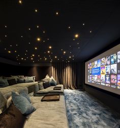 a large room with several couches and pillows on the floor, in front of a projector screen