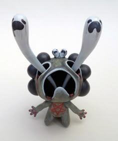 an odd looking toy with big eyes and two hands on it's head, sitting in front of a white background