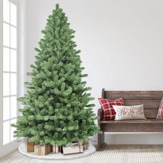 a small christmas tree sitting next to a wooden bench in a room with white walls