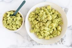 two bowls filled with macaroni and cheese on top of a marble counter