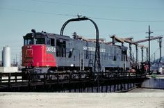 a red and black train traveling down tracks next to power lines