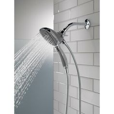 a shower head with water running from it's spout in a white tiled wall