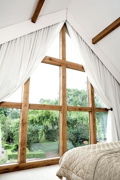 a bed sitting under a window next to a white blanket on top of a bed