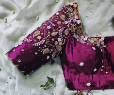 two pieces of clothing laying on top of a white cloth covered in beads and flowers