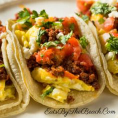 three tacos are sitting on a plate with salsa and other toppings around them