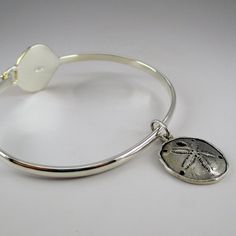 "This sterling silver Scallop Shell Bangle features a silver band with a ridged, gold vermeil scallop shell. The bangle accommodates large spacer beads and traditional charms. Marked Brown County Silver and Sterling inside the band. Also marked S.W.P. for designer Steven Wesley Patterson. Brand new, never worn condition. Available in medium only. Medium - 7.25\" Approximate weight is 14 grams *Sand dollar charm sold separately." Adjustable Silver Bracelet With Ocean-inspired Style, Adjustable Silver Bracelets With Ocean-inspired Style, Adjustable Silver Ocean-inspired Bracelets, Silver Adjustable Ocean-inspired Bracelets, Adjustable Silver Charm Bracelet With Starfish, Silver Shell-shaped Ocean-inspired Jewelry, Silver Shell Jewelry With Lobster Clasp, Silver Shell-shaped Jewelry With Lobster Clasp, Nickel-free Adjustable Ocean-inspired Jewelry