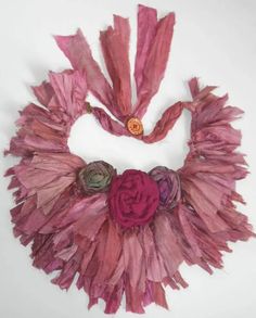 a pink scarf with flowers on it is hanging from the wall in front of a white background