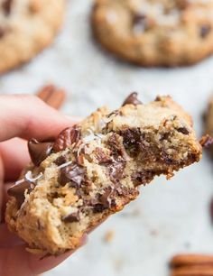 someone holding a chocolate chip cookie in their hand