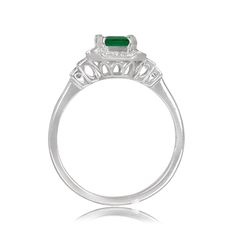 A geometric gemstone and diamond ring that features a lively natural emerald with a green saturation. Surrounding the center diamond is a halo of baguette-cut diamonds and round-cut diamonds. Additional baguette-cut diamonds are set on the shoulder. This ring is handcrafted in 14k white gold.
The approximate emerald weight of this ring is 0.79 carats. The total approximate diamond weight of this ring is 0.54 carats.
The measurements of this ring including the halo are approximately 9.60mm x 8.35 Emerald Cut Emerald Ring With Baguette Diamonds, May Birthstone Baguette Cut Diamond Rings, Art Deco Baguette Cut Emerald Ring, Green Diamond Rings With Baguette Cut, Green Baguette Diamond Rings, May Birthstone Emerald Ring With Baguette Diamonds, Green Emerald Ring With Baguette Diamonds For May Birthstone, Emerald Cut Emerald Ring, Ring With Halo