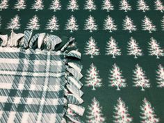 a green and white checkered blanket with christmas tree designs on it's edges