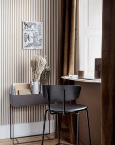 two chairs sitting next to each other in front of a wall with vertical stripes on it