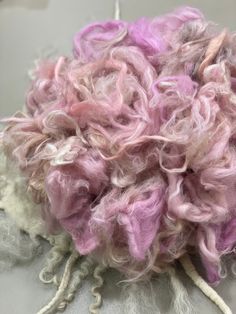 a pile of pink and white yarn sitting on top of a gray cloth covered table