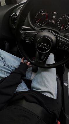 a person sitting in the driver's seat of a car with their feet on the steering wheel