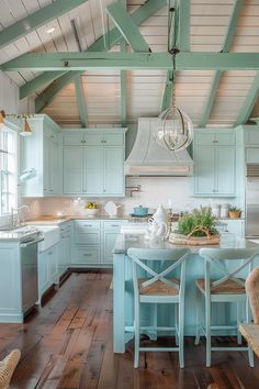 a kitchen with blue cabinets and wooden floors is pictured in this image, there are two chairs at the center of the table