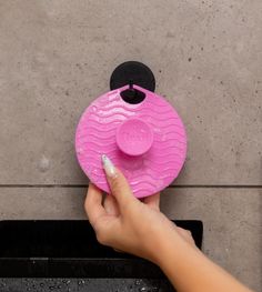 a person is holding a pink object in their left hand and pointing it at the ground