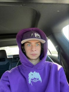 a young man in a purple hoodie sitting in the back seat of a car