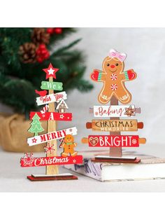 two wooden christmas trees with gingerbreads and merry signs on them next to a pine tree