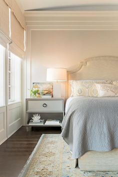 a bedroom with a bed, night stand and rug on the floor in front of it