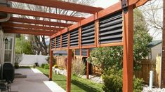 an outdoor covered patio area with wooden pergols and green grass on the side