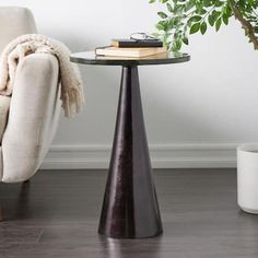 a living room with a chair, table and potted plant on the floor next to it