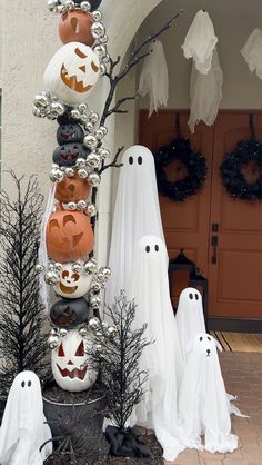 a group of halloween pumpkins sitting on top of a planter in front of a house