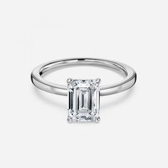 an emerald - cut diamond ring with a thin band on the side, set in 18k white gold