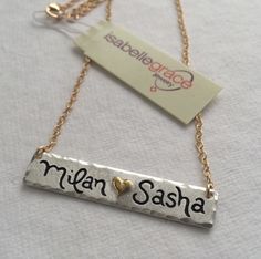 Double Name Bar Necklace - A gorgeous holiday gift, this is the perfect piece to layer with a longer necklace! The Double Name Bar Necklace features a (0.999) fine silver bar custom inscribed with two names or sets of initials separated by a 22kt gold heart. The edges are also slightly hammered to give it a distressed look. The name bar is approximately 1 3/4 inches long but the size may vary depending on personalization. Also has a matte finish! Hand Stamped Nameplate Jewelry For Anniversary, Hand Stamped Nameplate Jewelry For Anniversary Gift, Engraved Nameplate Necklaces, Adjustable Engraved Nameplate Necklaces, Hand Stamped Nameplate Necklace For Anniversary, Sterling Silver Nameplate Necklace Hand Stamped, Sterling Silver Hand-stamped Nameplate Necklace, Sterling Silver Hand Stamped Nameplate Necklaces, Handmade Nameplate Necklace For Anniversary