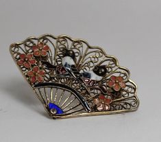 "Consider this vintage hand enameled brooch, depicting two little hand painted black and white enameled birds sitting atop cherry blossom blanches with 5 pink cherry blooms. Scalloped edging on a filigree background off plated sterling and a safety locking clasp. This broached pin fans out in both directions from the blue enameled, center pin (see photo's). Age and manufacture is unknown, yet on the pinned backside there are 4 stamped identifying numbers of S925 that is very hard to read and is reference to the plated sterling silver. No test was taken of the plated material but, is likely gold plated. Craftsmanship shows on this very dainty looking piece of vintage jewelry.    The condition on this vintage piece of jewelry as a Excellent with no flaws or damage done to any of the delicate Vintage Black Enamel Pin For Gift, Victorian Style Enamel Pin Gift, Unique Handmade Collectible Enamel Pin, Vintage Handmade Enamel Pin Gift, Silver Enamel Pin For Wedding, Handmade Enamel Brooches For Gifts, Silver Enamel Wedding Pin, Victorian Enamel Pin Collectible, Victorian Enamel Collectible Pin