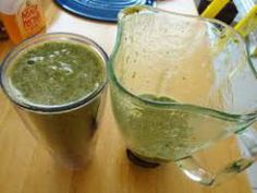 two glasses filled with green liquid sitting on top of a wooden table