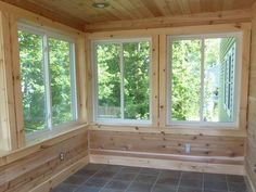 an empty room with wooden walls and windows