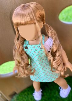 a doll with blonde hair and blue dress standing in front of a fake grass area