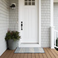 a white front door on a gray house with potted plants in the foreground