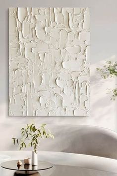 a white painting on the wall above a table