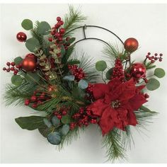 a christmas wreath with poinsettis and greenery hanging on a white wall