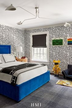 a bedroom with blue and white bedding, black and white wallpaper and two chairs