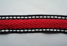 a red and black rope with white stitching on it's end is shown