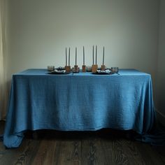 a table with four candles on it in front of a white wall and wood floor