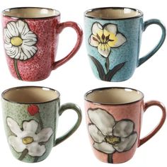 four coffee mugs with flowers painted on them are lined up in different colors and designs