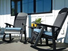 two black rocking chairs sitting on top of a wooden deck next to a table and chair