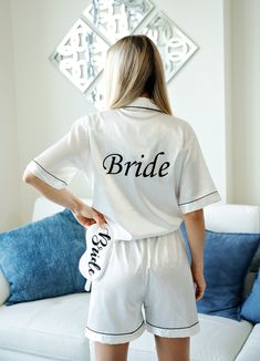 a woman standing in front of a white couch wearing a bride pajama set