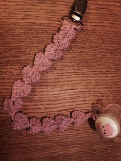 a pink crochet key chain with a teddy bear charm attached to it on a wooden surface