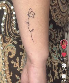 a woman's arm with a small flower tattoo on it