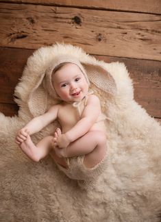 a baby in a bunny costume is sitting on a sheep